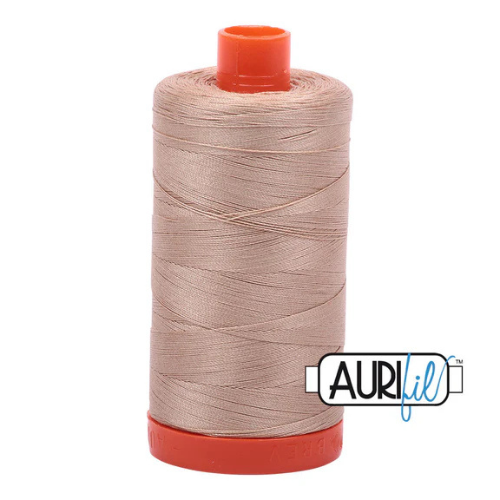 Spool of Aurifil thread with red cap on a white background