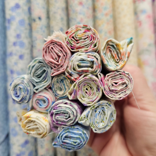 Bouquet of colorful fabric rolls held by a hand with a fabric background