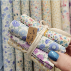 Stack of floral fabric rolls tied with twine.