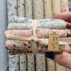 Packaged fabric rolls with a visible brand tag held by a hand.