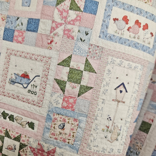 Quilt with various patterns including birds, flowers, and animals on a patchwork background.