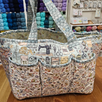 Large tote bag with sewing-themed pattern in a store setting