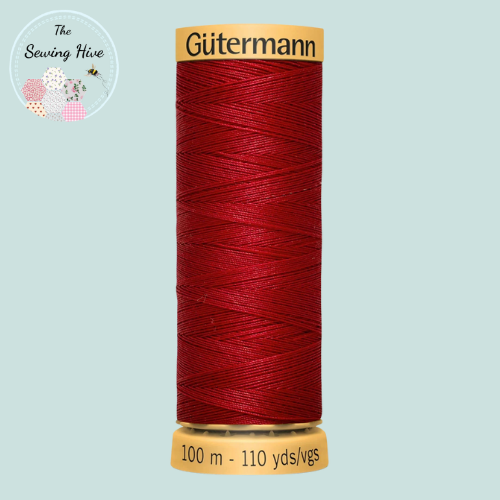Spool of red Gutermann thread on a light blue background