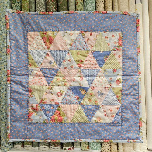 Patchwork quilt with floral patterns displayed against a fabric background