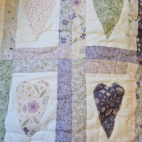 Patchwork quilt with floral heart designs and a vertical stripe.