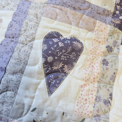 Quilt with floral heart design in a patchwork pattern