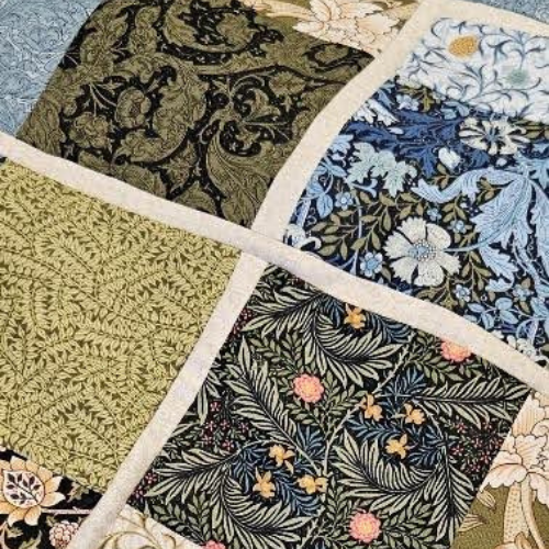 Quilt with various floral and geometric patterns in a patchwork design.